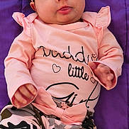 Kevani joined the competition — help win amazing prizes! baby, bow, camo_pattern, child, cute, drool, face, happy, headband, indoor, infant, long_sleeve, lying_down, pants, person, pink_clothing, portrait, purple_blanket, smile, toddler