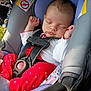 baby, car_seat, child, cute, fabric, face, hand, indoors, infant, newborn, peaceful, red_pants, resting, safety, seatbelt, sleeping, transport, warning_label, white_shirt, young_child
