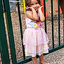 child, girl, dress, playground, gate, shoes, posing, outdoor, smiling, cute, fence, play_equipment, colorful, happy, young, person, toddler, fashion, portrait, park