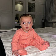 Maia joined the competition — help win amazing prizes! baby, infant, child, onesie, bed, blanket, indoor, portrait, sitting, curious, face, expression, room, window, curtains, mirror, lighting, sleepwear, hands, feet