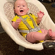 John-Michael joined the competition — help win amazing prizes! baby, child, yellow_onesie, baby_rocker, smiling, happy, indoor, carpet, patterned_cushion, sitting, straps, face, person, infant, toy, furniture, dog_cage, pet, home, vibration_control