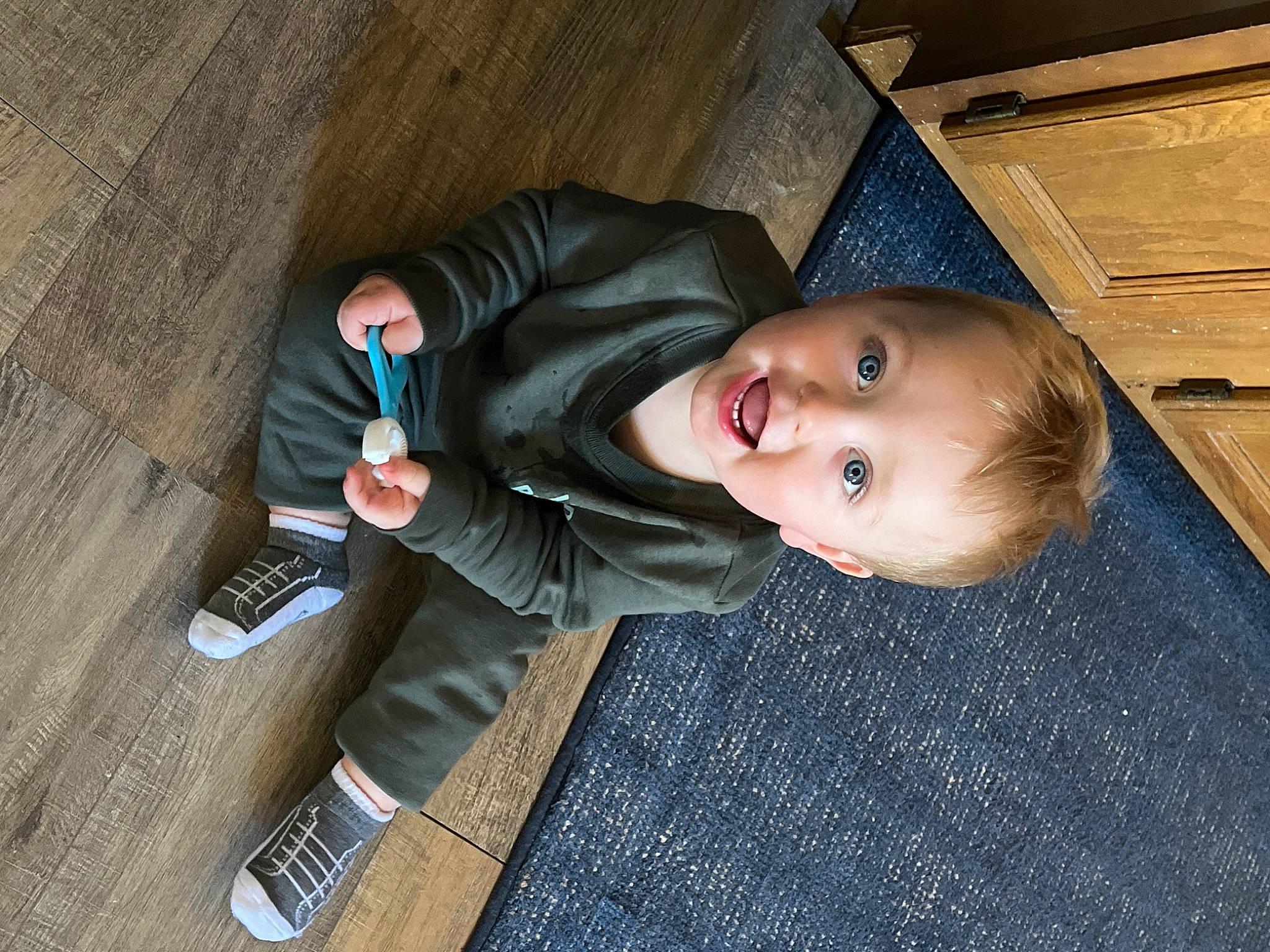 Braxton is registered to the contest to win money with this photo: baby, baby_toddler_clothing, cheek, child, comfort, crawling, denim, floor, flooring, foot, fun, hardwood, person, room, sitting, skin, smile, toddler, tree, wood