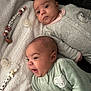baby, infant, two_babies, blanket, pacifier, cute, smiling, happy, clothing, gray_outfit, green_outfit, lying_down, indoor, soft_texture, face, head, person, child, newborn, cozy