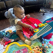 Malyk is registered to the contest to win money with this photo: toddler, child, toy, playmat, backpack, elephant, plush_toy, floor, couch, indoor, baby_toy, colorful, socks, wood_floor, phone_case, cables, living_room, curious, playing, person