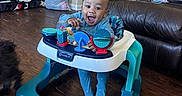 Malyk joined the competition — help win amazing prizes! baby, baby_walker, bag, blue_onesie, casual, child, floor, furniture, happy, home, indoor, joy, leather_couch, living_room, person, plastic, play, smile, toy, wood_floor
