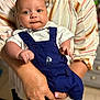 Liam is registered to the contest to win money with this photo: baby, infant, person, clothing, overall, white_shirt, bowtie, hand, ring, nail_polish, face, eyes, indoor, adult, striped_shirt, furniture, portrait, cute, holding, child