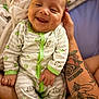 baby, smiling, infant, onesie, green, white, tattoo, arm, hand, person, cute, happy, closeup, face, skin, child, comfort, indoor, family, love