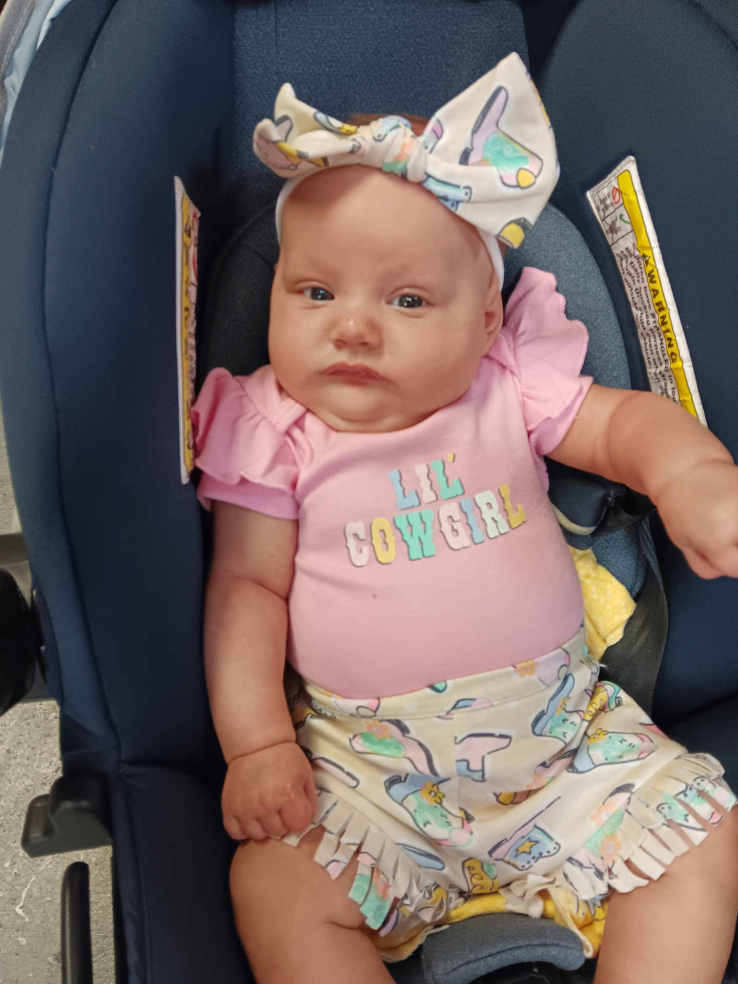 Blakelynn joined the competition — help win amazing prizes! baby, infant, car_seat, headband, bow, pink_shirt, shorts, clothing, cute, child, person, sitting, serious_expression, indoor, pattern, fringe, cowgirl, outfit, skin, hand