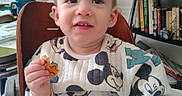 Aaron joined the competition — help win amazing prizes! toddler, child, baby, portrait, smiling, happy, high_chair, indoor, kitchen, snack, food, eating, hand, face, eyes, hair, clothing, mickey_mouse, furniture, bookshelf