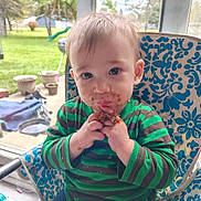Aaron joined the competition — help win amazing prizes! baby, child, toddler, portrait, sitting, eating, snack, food, crumbs, smiling, face, eyes, hands, striped_shirt, green_clothing, chair, outdoor, garden, patio, sunlight