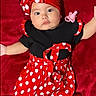 baby, infant, red_clothing, polka_dots, headband, pacifier, black_shirt, white_socks, lying_down, cute, child, portrait, soft_blanket, adorable, baby_fashion, baby_accessories, red_background, smiling, small_ears, child_fashion