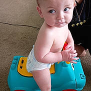 Waylon joined the competition — help win amazing prizes! toddler, child, toy_car, diaper, indoor, carpet, blue, yellow, red, person, adult, curious, playful, plastic_toy, car, floor, young_child, baby, hand, face