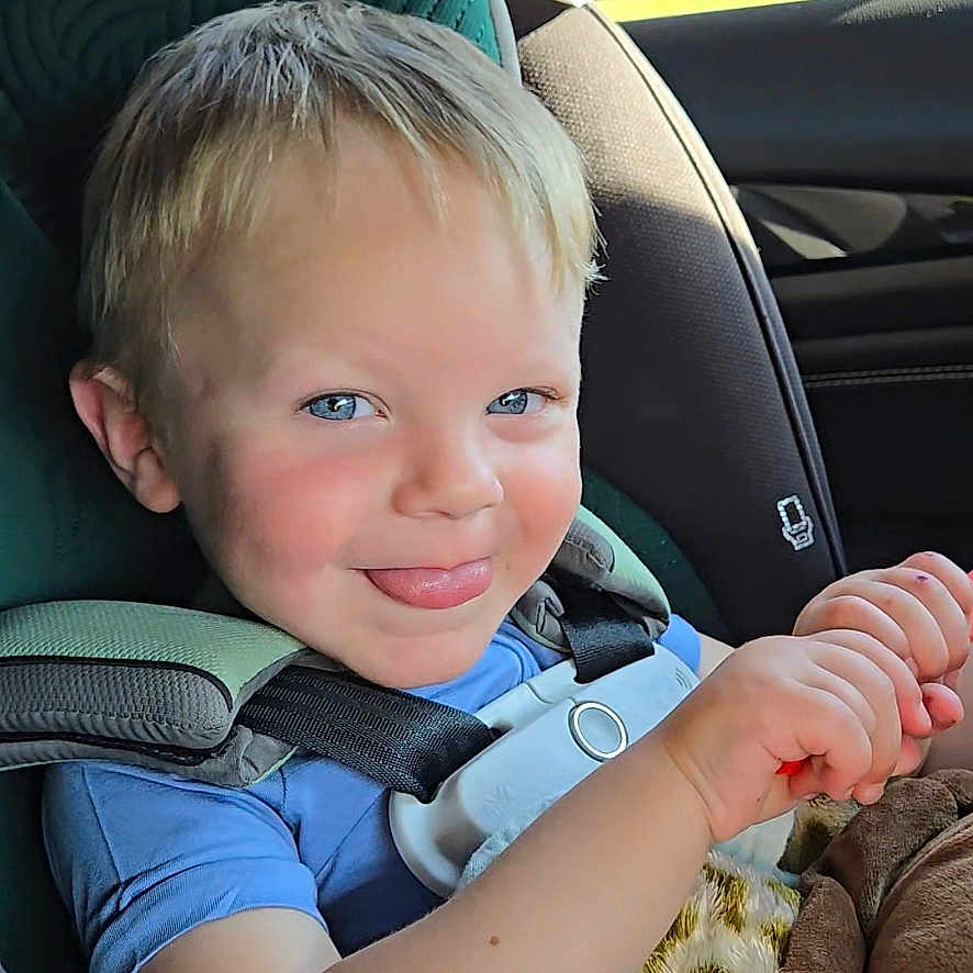 Levi is registered to the contest to win money with this photo: accessories, baby, bodypart, clothing, coat, cushion, face, finger, hand, happy, head, homedecor, jacket, pants, person, photography, portrait, smile, transportation, vehicle