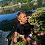 Noé participe au concours pour gagner de l'argent avec cette photo : baby, black_shirt, child, diaper, footwear, grass, greenery, house, lake, nature, outdoor, person, reflection, scenic, shadow, sitting, summer, sunlight, trees, water