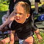 adult, baby, black_shirt, blurred_background, child, diaper, expression, face, grass, greenery, hands, legs, nature, outdoor, person, shadow, sitting, skin, summer, sunlight
