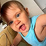 toddler, child, blue_eyes, blue_shirt, indoor, couch, pillow, curious, expression, smiling, skin, face, arm, hand, toy, cable, closeup, person, home, casual