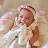 adorable, baby, child, cloth, cute, fabric, happy, headband, indoors, infant, petals, pink_bow, pink_petals, playful, portrait, sitting, smiling, soft_background, textile, white_dress