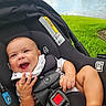 baby, car_seat, child, clothing, cute, daylight, expression, grass, hands, happy, infant, legs, nature, outdoor, park, person, safety, seatbelt, smiling, water_fountain