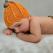 Nathaniel is registered to the contest to win money with this photo: baby, infant, child, knitted_hat, orange, lying_down, fluffy_surface, cute, soft_texture, skin, portrait, indoors, sleepwear, newborn, cozy, warm, small_hands, resting, headwear, peaceful