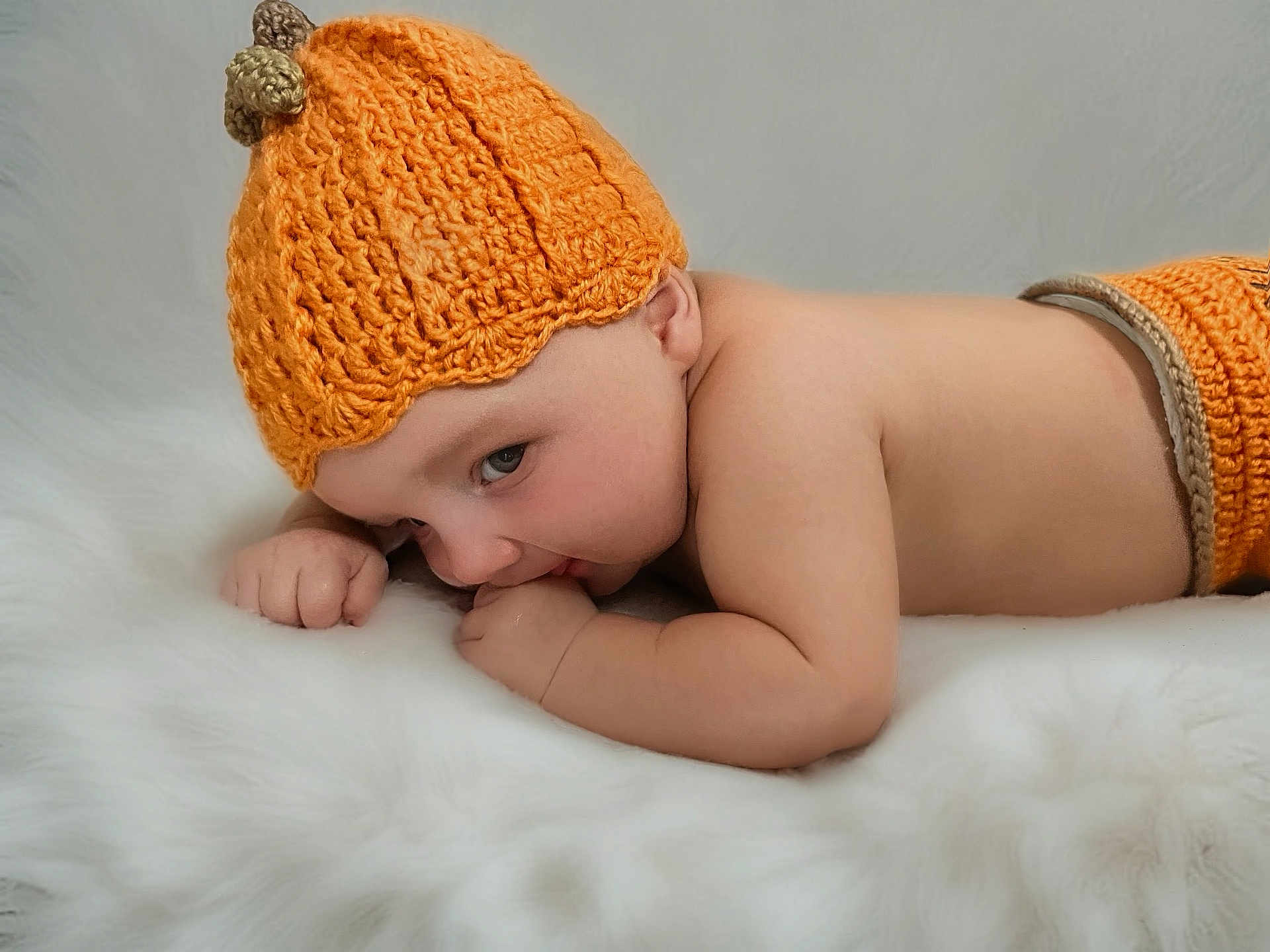 Nathaniel is registered to the contest to win money with this photo: baby, infant, child, knitted_hat, orange, lying_down, fluffy_surface, cute, soft_texture, skin, portrait, indoors, sleepwear, newborn, cozy, warm, small_hands, resting, headwear, peaceful