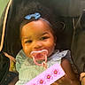 baby, infant, pacifier, stroller, blue_bow, smile, child, cute, portrait, happy, indoor, clothing, face, headband, young_child, person, sitting, skin_tone, social_media, emoji