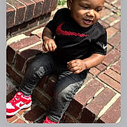 Dmirio Gibson joined the competition — help win amazing prizes! toddler, child, sitting, brick, steps, black_shirt, nike, red_sneakers, curly_hair, earrings, outdoor, happy, smiling, casual_clothing, daylight, person, fashion, cute, playful, portrait