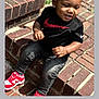 toddler, child, sitting, brick, steps, black_shirt, nike, red_sneakers, curly_hair, earrings, outdoor, happy, smiling, casual_clothing, daylight, person, fashion, cute, playful, portrait