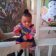 Liam joined the competition — help win amazing prizes! toddler, child, baby, denim_overalls, colorful_clothing, striped_sleeves, porch, railing, hand, adult, plant, foliage, halloween_decoration, ghost, smiling, outdoor, daylight, person, expression, holding