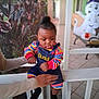 toddler, child, baby, denim_overalls, colorful_clothing, striped_sleeves, porch, railing, hand, adult, plant, foliage, halloween_decoration, ghost, smiling, outdoor, daylight, person, expression, holding