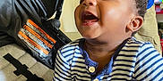 Mecca is registered to the contest to win money with this photo: baby, child, smiling, laughing, striped_clothing, onesie, stroller, person, hand, indoor, happy, cute, infant, seat, fabric, playful, tablet, background, casual, joyful
