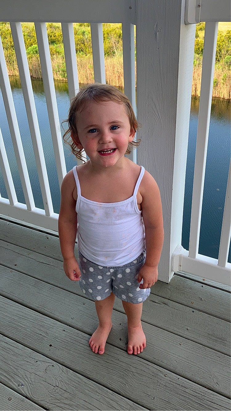 Stella joined the competition — help win amazing prizes! baby_toddler_clothing, barefoot, child, dress, fence, fun, happy, joy, leg, leisure, pattern, person, shorts, skin, sleeve, smile, standing, toddler, tree, waist