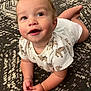 baby, infant, child, onesie, animal_print, carpet, patterned_rug, cute, smiling, happy, lying_down, hands, curly_hair, indoors, portrait, closeup, skin, face, eyes, toddler