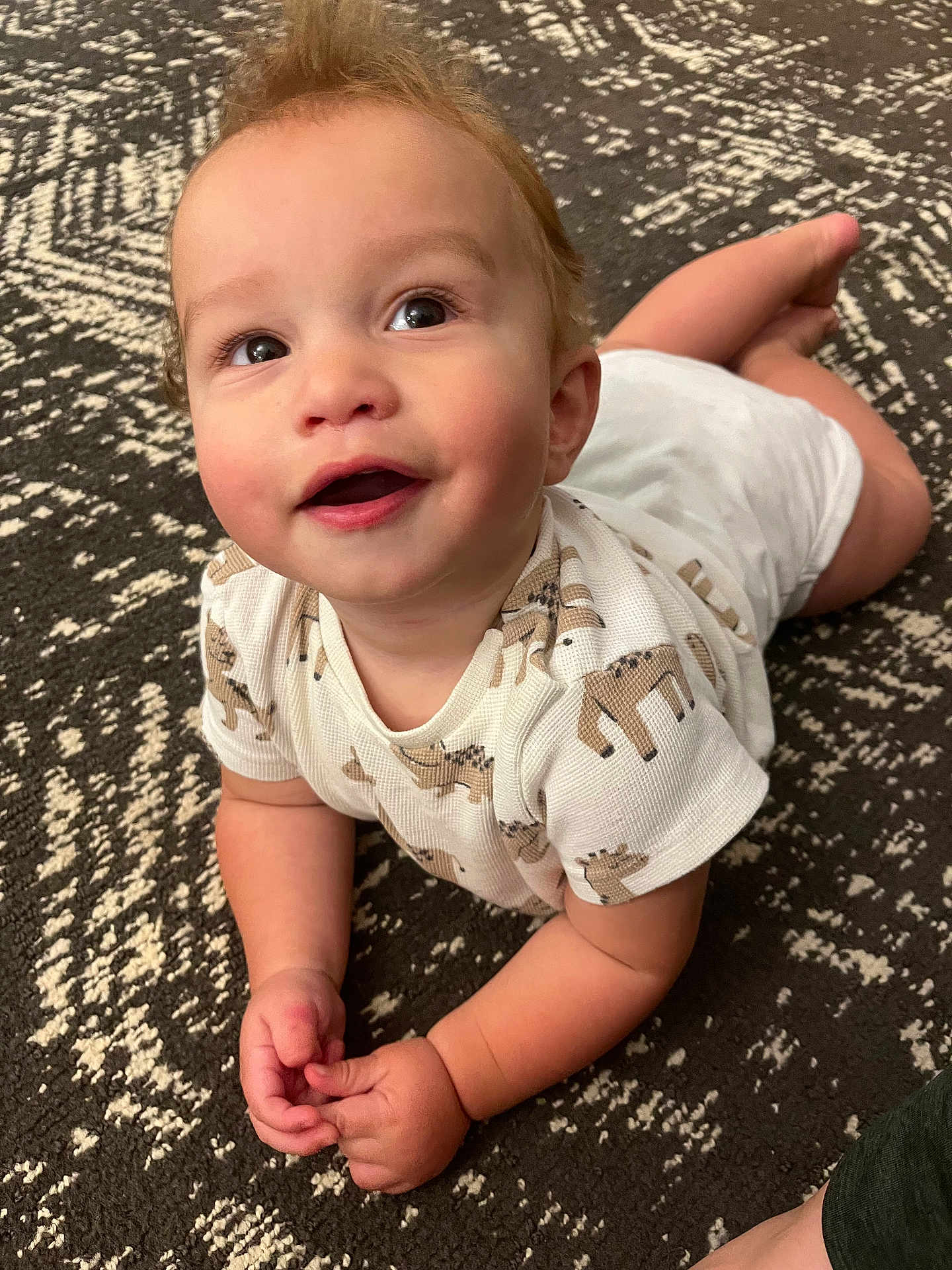 Adare joined the competition — help win amazing prizes! baby, infant, child, onesie, animal_print, carpet, patterned_rug, cute, smiling, happy, lying_down, hands, curly_hair, indoors, portrait, closeup, skin, face, eyes, toddler