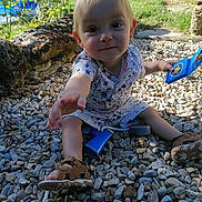 Louis participe au concours pour gagner de l'argent avec cette photo : blue_toy, child, curious_expression, garden, greenery, nature, outdoor, patterned_clothing, pebbles, playful, reaching_hand, sandals, shadow, sitting, stone_wall, summer, sunlight, toddler, toy, young_child