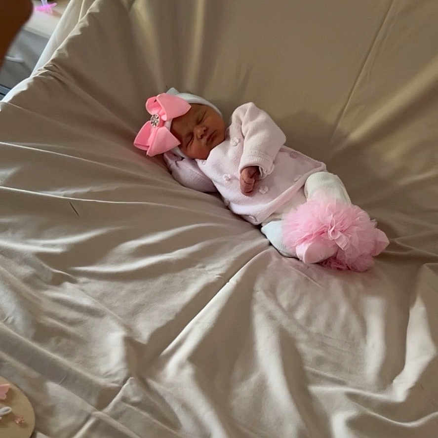 Billie a rejoint le concours — aidez-le/la à gagner de superbes lots ! adorable, baby, bed, blanket, child, comfort, cute, headwear, indoor, infant, lying_down, newborn, peaceful, person, pink_bow, pink_clothes, resting, sleeping, soft_fabric, white_clothes