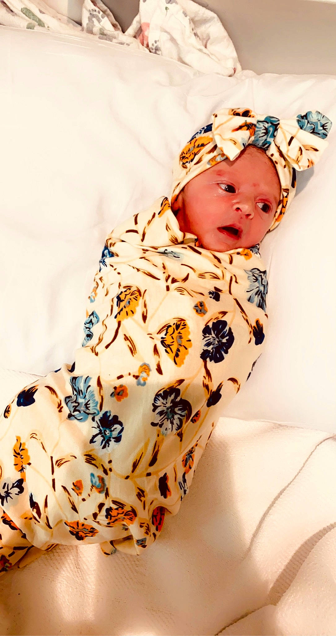 Shayne is registered to the contest to win money with this photo: arm, baby, baby_toddler_clothing, brown_hair, comfort, day_dress, dress, eyelash, face, fashion_accessory, fashion_design, headpiece, headwear, linens, neck, outerwear, pattern, peach, person, sleeve