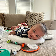 Arthur Augustus joined the competition — help win amazing prizes! baby, smiling, tummy_time, couch, cushion, toy, curly_hair, indoor, window_blinds, striped_clothing, play_mat, happy, child, infant, face, head, person, soft_toys, blanket, home