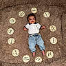 baby, infant, milestone_cards, blanket, denim_pants, polo_shirt, feet, face, smiling, lying_down, cute, child, milestone, firsts, indoors, soft_texture, circle, celebration, happy, portrait
