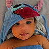 baby, infant, child, portrait, face, eyes, wide_eyed, looking_at_camera, hood, costume, monster, blue, red, blanket, bed, lying_down, indoor, close_up, adorable, photography