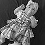 baby, bonnet, cap, clothing, costume, couch, doll, dress, face, figurine, furniture, hat, head, person, photography, portrait, sitting, skirt, tartan, toy