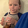 child, boy, indoor, mickey_mouse, cup, straw, drink, tshirt, person, face, short_hair, window_blind, hand, wall, casual_clothing, young, expression, holding, blue_clothing, portrait