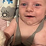 baby, smiling, blue_eyes, harness, close_up, infant, child, blanket, pattern, soft_skin, hand, face, cute, young, indoors, happy, person, portrait, baby_clothing, lying_down