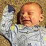Eric is registered to the contest to win money with this photo: baby, sleeping, smile, onesie, carpet, infant, face, child, cute, peaceful, clothing, pattern, starfish, shark, marine_life, soft_lighting, portrait, resting, young, indoors