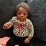 Eloni is registered to the contest to win money with this photo: baby, child, curly_hair, leopard_print, shirt, question_mark, guess_brand, couch, blanket, black_pants, indoor, seated, cute, curious, infant, portrait, soft_texture, clothing, hand, face