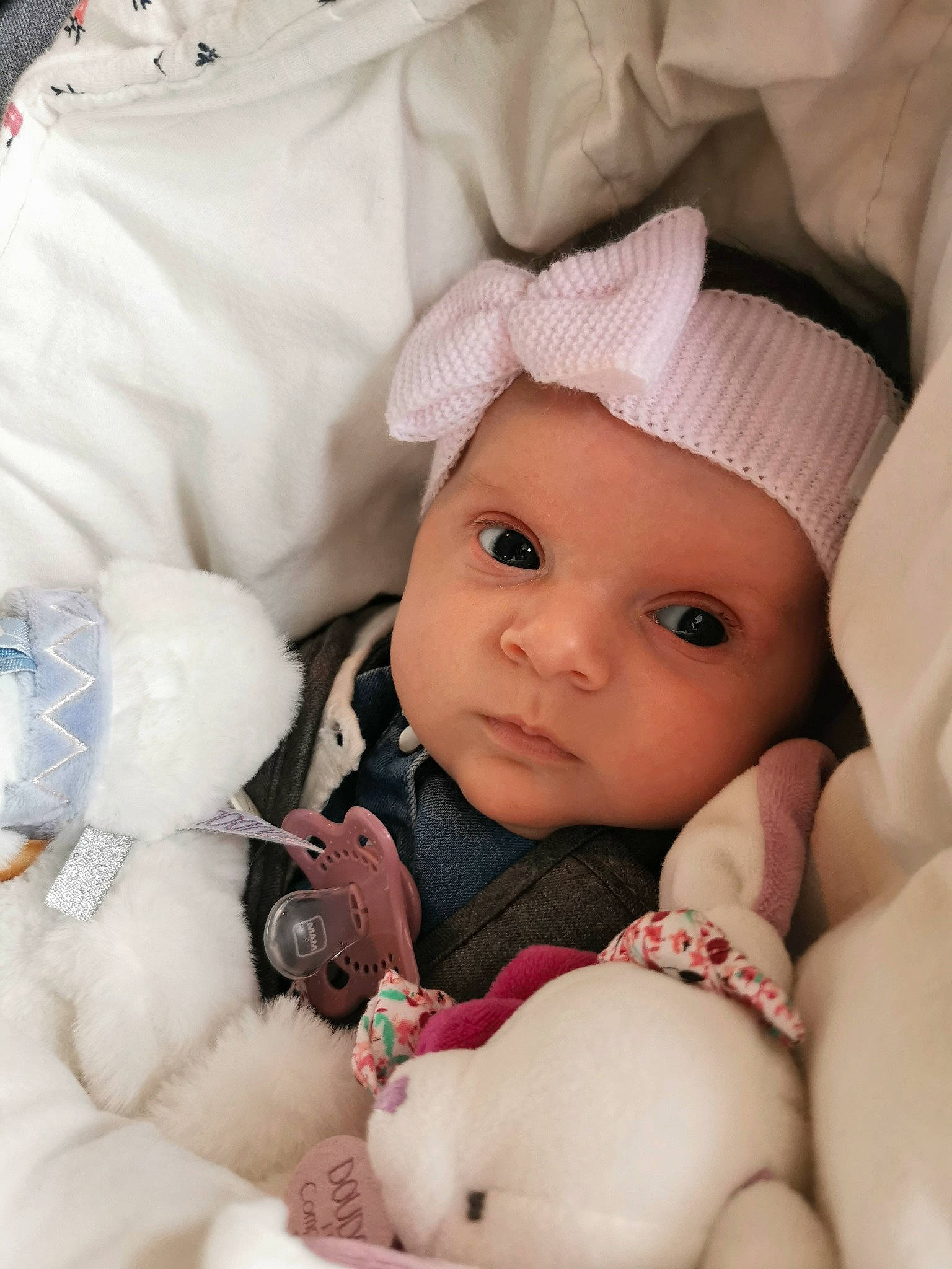 énola a rejoint le concours — aidez-le/la à gagner de superbes lots ! baby, baby_products, baby_sleeping, baby_toddler_clothing, cap, cheek, child, comfort, eye, face, headwear, linens, mouth, person, pink, product, room, skin, sleeve, textile