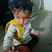 Kultej joined the competition — help win amazing prizes! toddler, child, curly_hair, yellow_cable, hand_holding, carpet, fan, remote_control, indoor, sitting, long_sleeve_shirt, white_shirt, patterned_shirt, person, floor, technology, adult_hand, candid, casual, cute