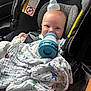 Jace is registered to the contest to win money with this photo: baby, blanket, bottle, car_seat, child, closeup, clothing, comfort, cute, face, happy, headgear, holding, indoor, infant, person, seatbelt, sitting, smiling, young