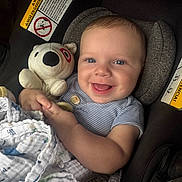 Jace is registered to the contest to win money with this photo: baby, smiling, blue_eyes, plush_toy, bear, blanket, car_seat, warning_label, infant, child, cute, happy, clothing, striped_shirt, indoor, portrait, holding, cuddly_toy, comfort, seat
