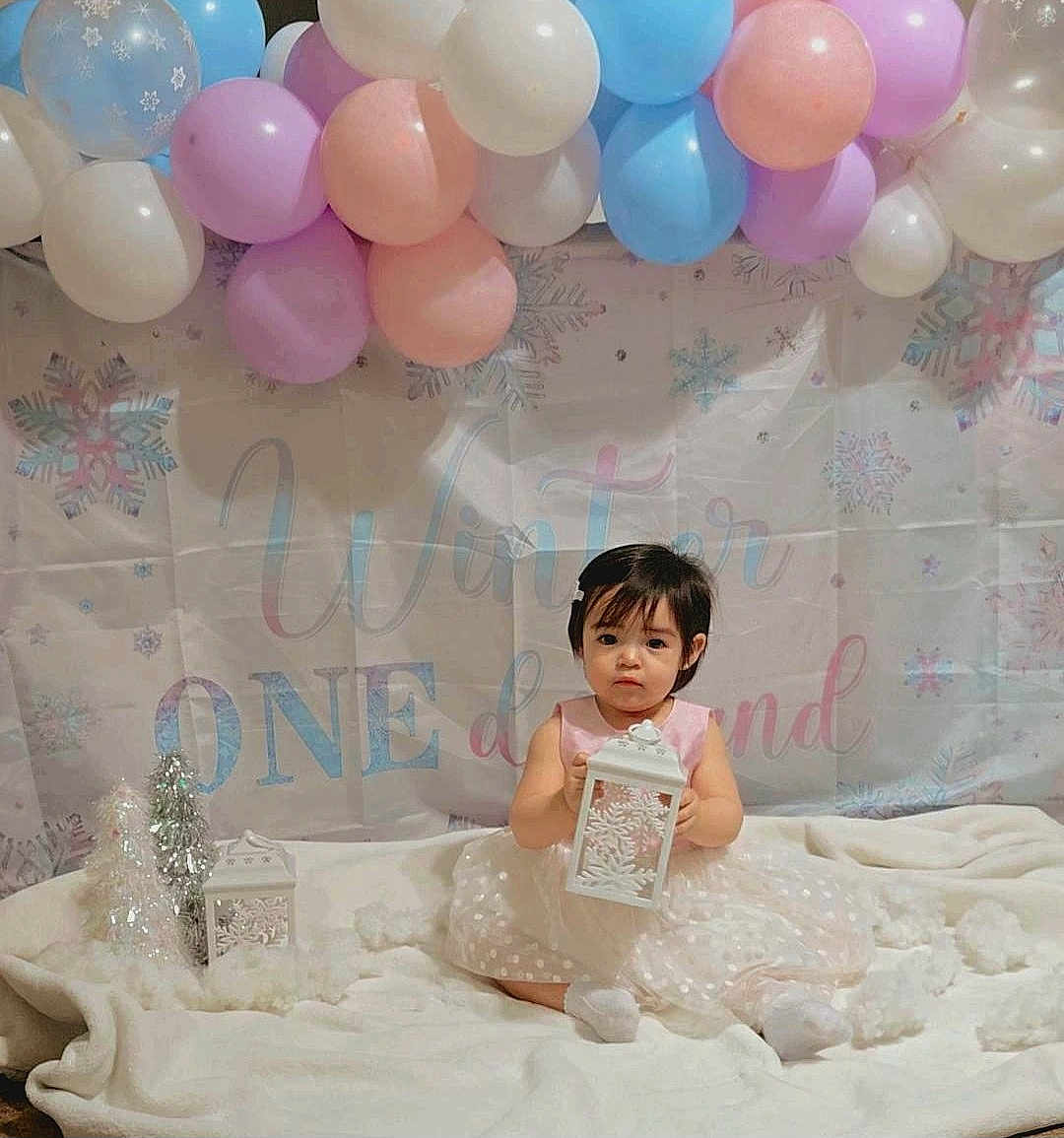 Roxanna is registered to the contest to win money with this photo: balloons, blanket, blue, celebration, child, cute, decoration, dress, festive, holiday, indoor, lantern, pink, portrait, silver, sitting, snowflakes, toddler, white, winter