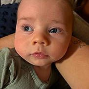 Tate is registered to the contest to win money with this photo: arm, baby, casual, child, closeup, clothing, curious, expression, eyes, face, human, indoors, infant, person, portrait, resting, skin, soft_skin, tattoo, warm_light